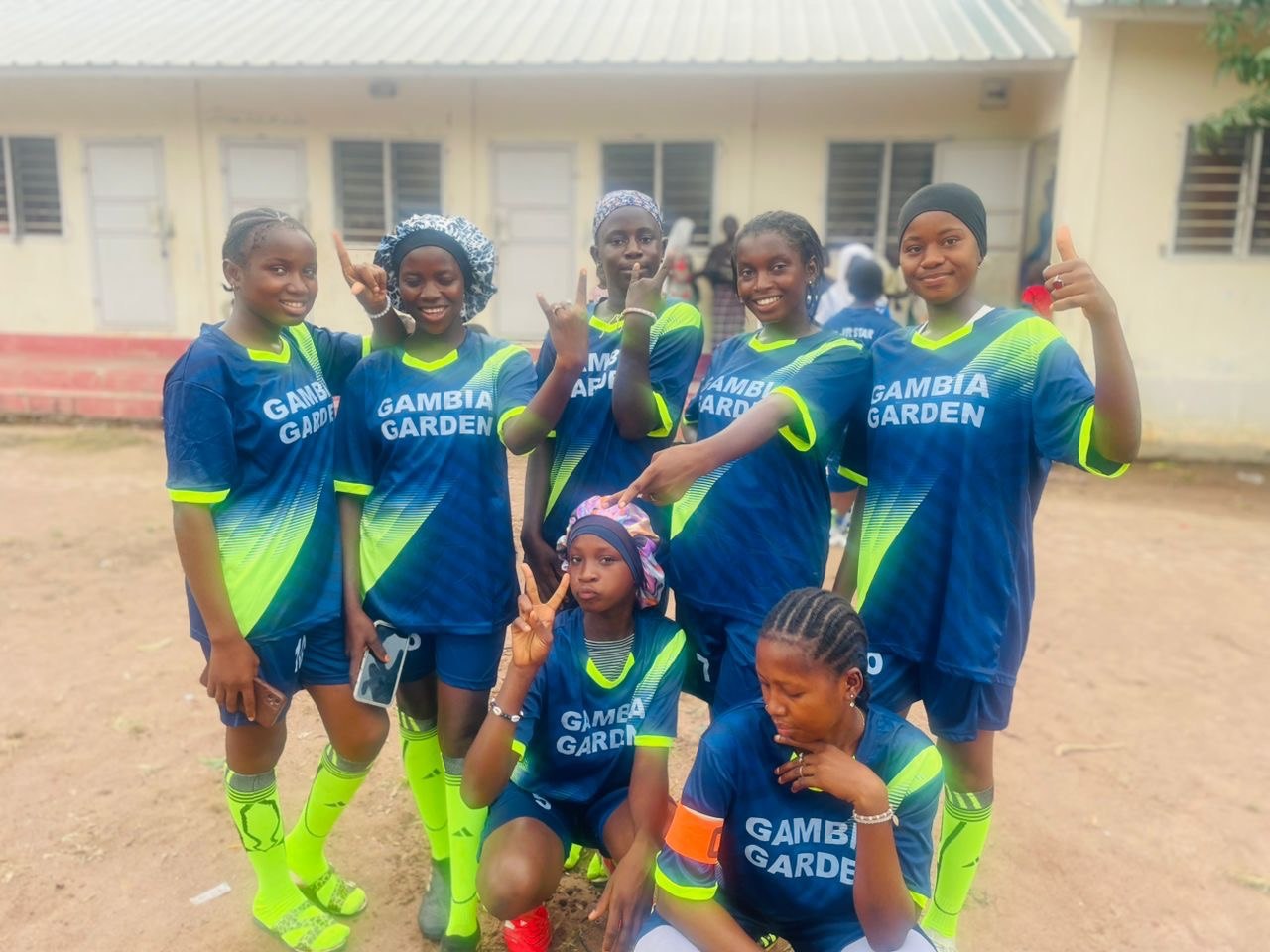 Players together wearing blue and lime Gambia Garden jerseys