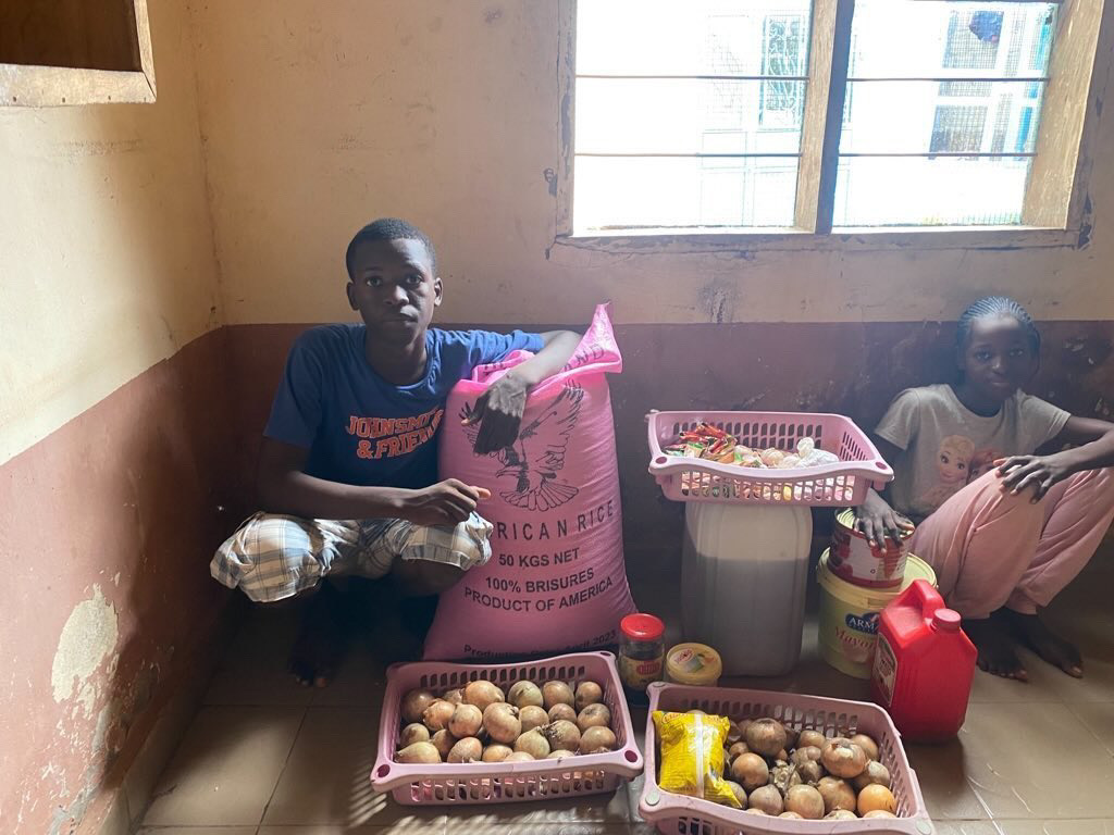 Two young people beside rice and other food supplies