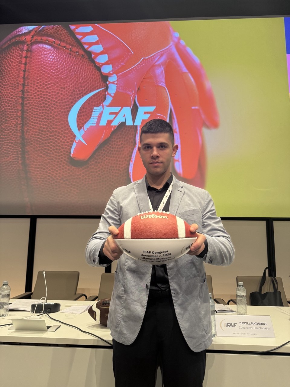 A co-founder holding a commemorative football marked with the Congress date and venue.