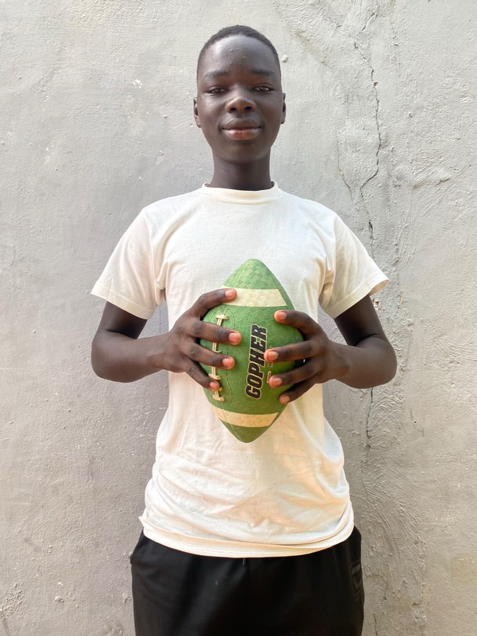 A young community member holding a football